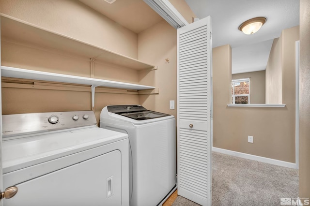 clothes washing area featuring laundry area, baseboards, washer and clothes dryer, and light colored carpet