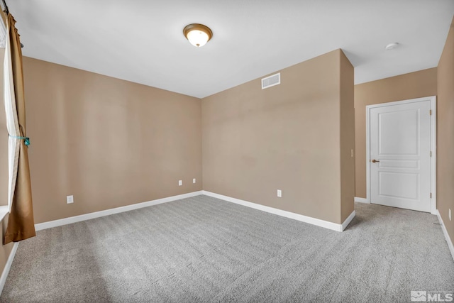 empty room with carpet floors, baseboards, and visible vents