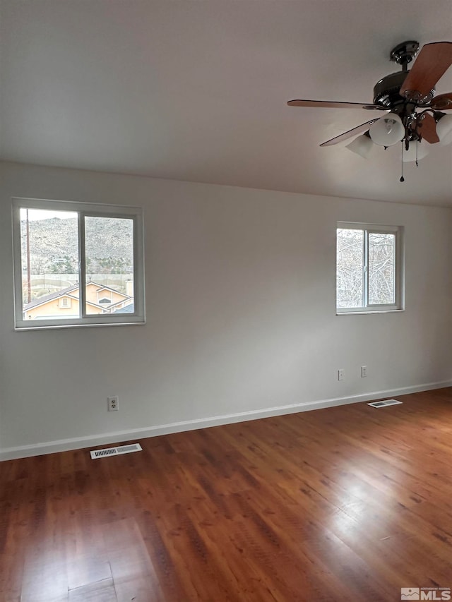 spare room with dark hardwood / wood-style floors, a healthy amount of sunlight, and ceiling fan