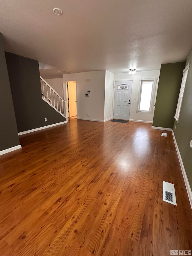 unfurnished living room featuring wood-type flooring and a textured ceiling