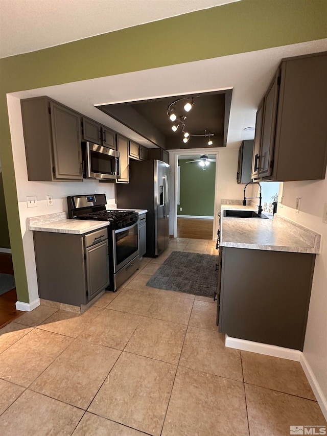 kitchen with a tray ceiling, sink, light tile patterned floors, and stainless steel appliances