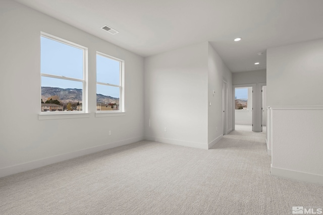 unfurnished room with a mountain view and light colored carpet