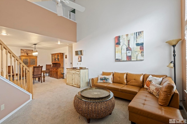 living room with carpet flooring, a towering ceiling, and ceiling fan