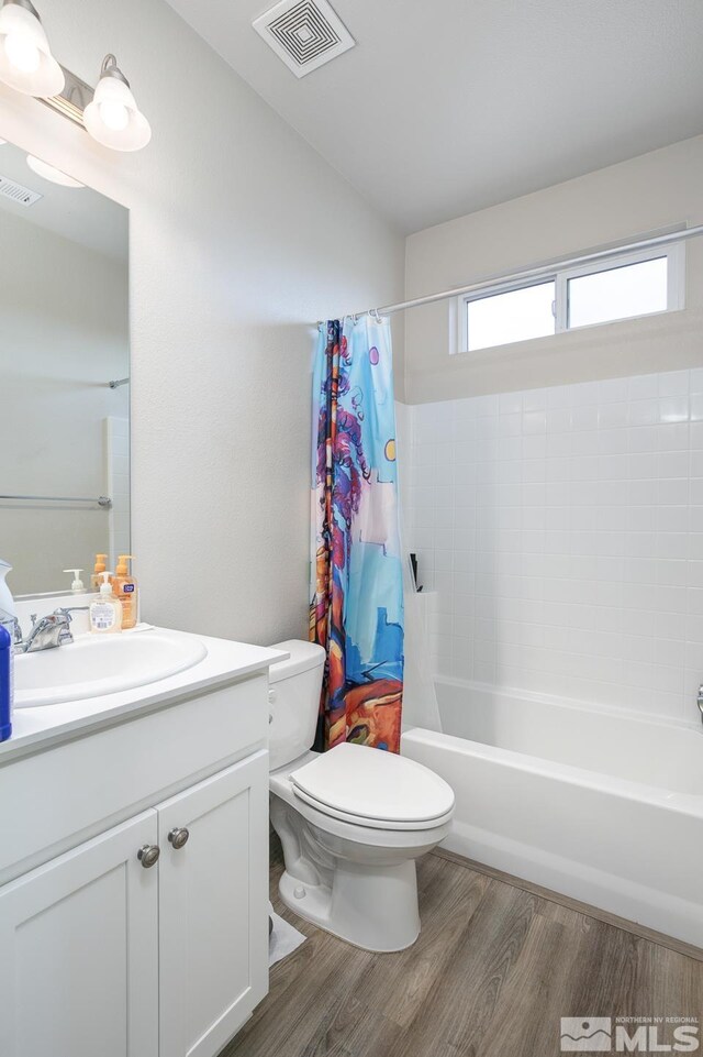 full bathroom featuring hardwood / wood-style flooring, vanity, toilet, and shower / bathtub combination with curtain