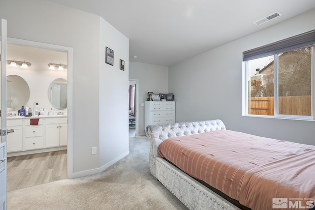 carpeted bedroom with sink and connected bathroom