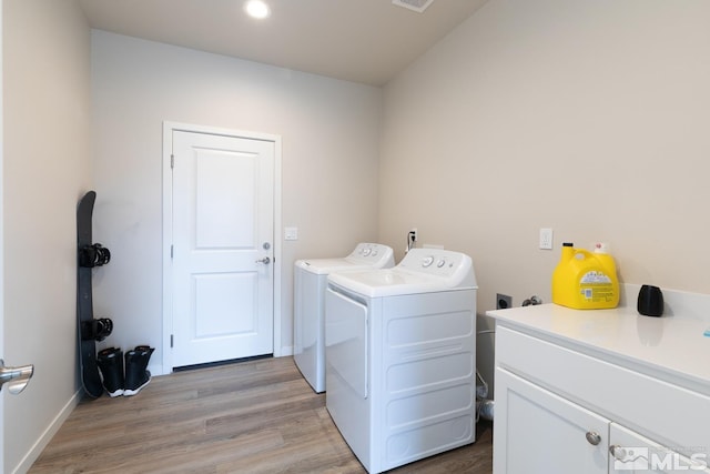 laundry area with cabinets, light wood-type flooring, and washing machine and dryer