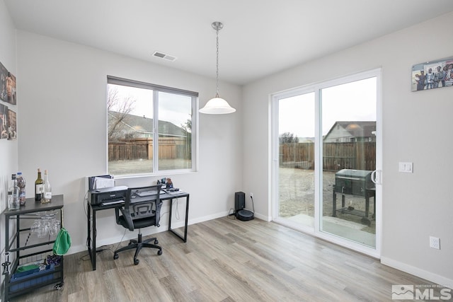 office area with light hardwood / wood-style floors and a healthy amount of sunlight