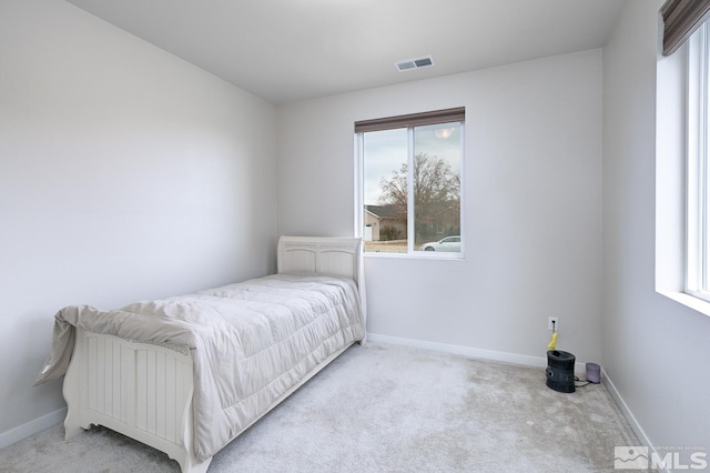 bedroom with multiple windows and light carpet