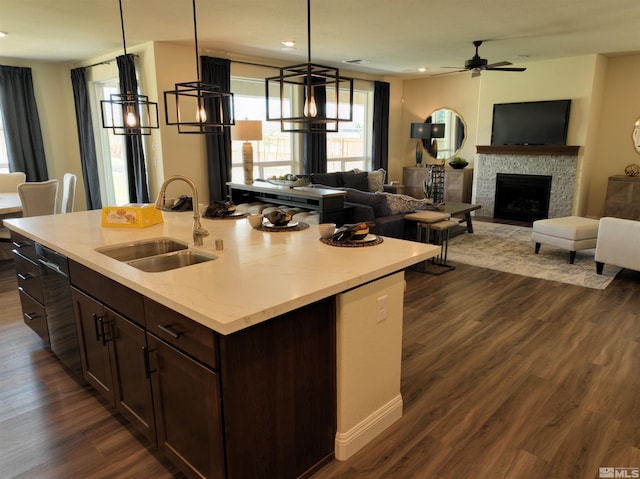 kitchen with pendant lighting, sink, dark wood-type flooring, and a center island with sink