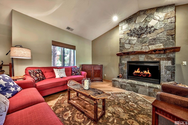 living room with a stone fireplace, light wood-type flooring, and lofted ceiling