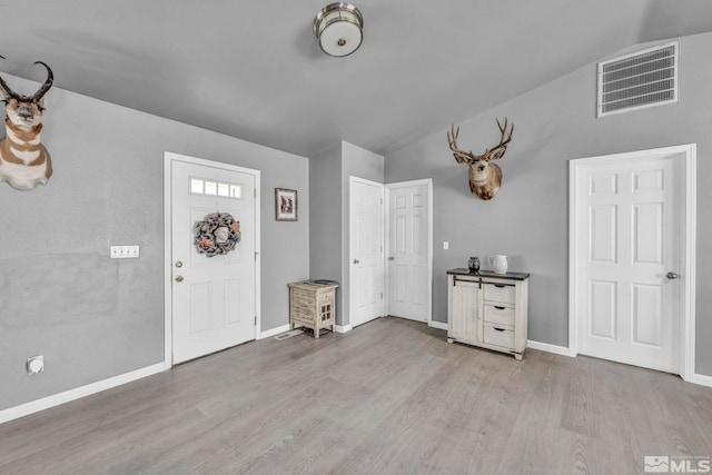 entrance foyer with light wood-type flooring and vaulted ceiling