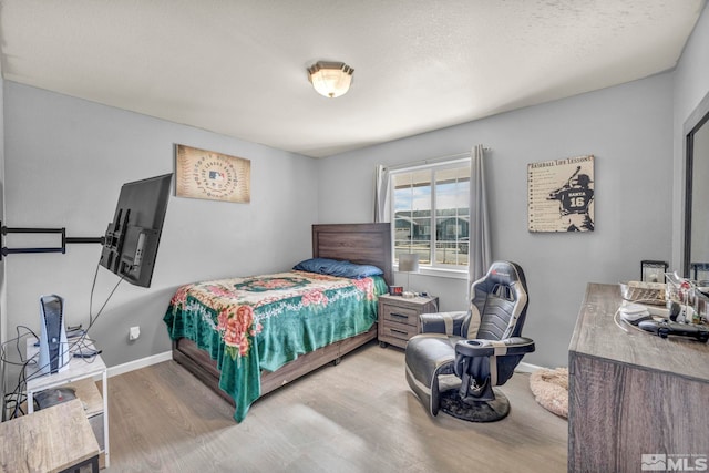 bedroom featuring light hardwood / wood-style floors and a textured ceiling