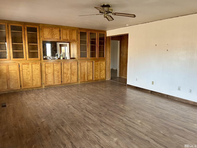 unfurnished living room featuring dark hardwood / wood-style flooring, built in features, and ceiling fan