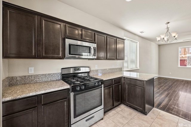 kitchen with kitchen peninsula, appliances with stainless steel finishes, pendant lighting, an inviting chandelier, and light hardwood / wood-style floors