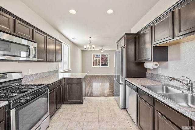 kitchen with sink, hanging light fixtures, light tile patterned floors, ceiling fan with notable chandelier, and appliances with stainless steel finishes