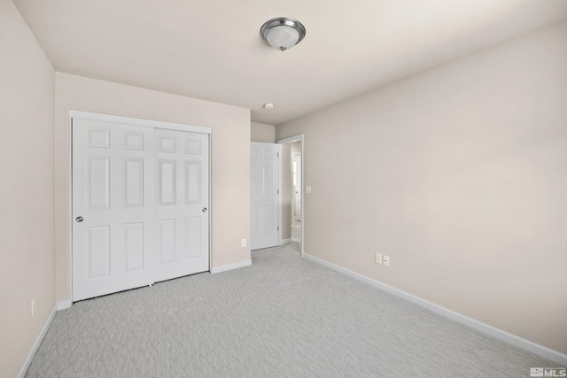 unfurnished bedroom featuring a closet and light colored carpet