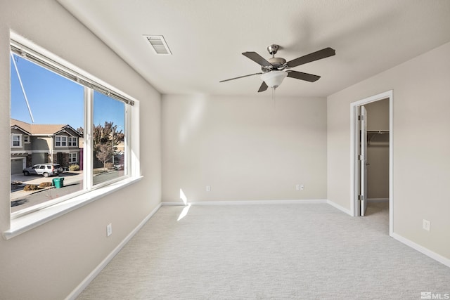 unfurnished bedroom with ceiling fan, light colored carpet, a walk in closet, and a closet