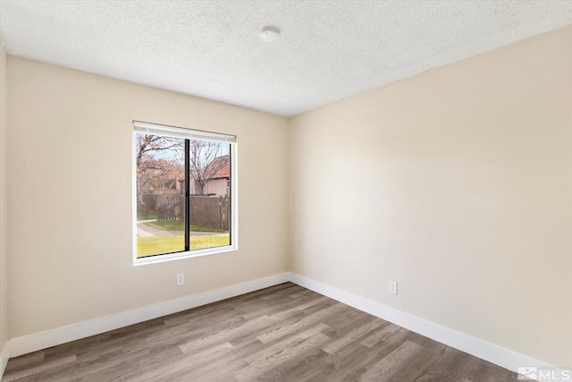 spare room featuring a textured ceiling and light hardwood / wood-style flooring