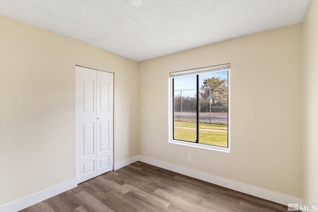 unfurnished bedroom with light hardwood / wood-style floors, a textured ceiling, and a closet