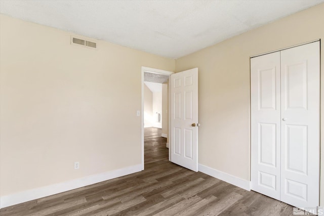 unfurnished bedroom with a closet, wood-type flooring, and a textured ceiling