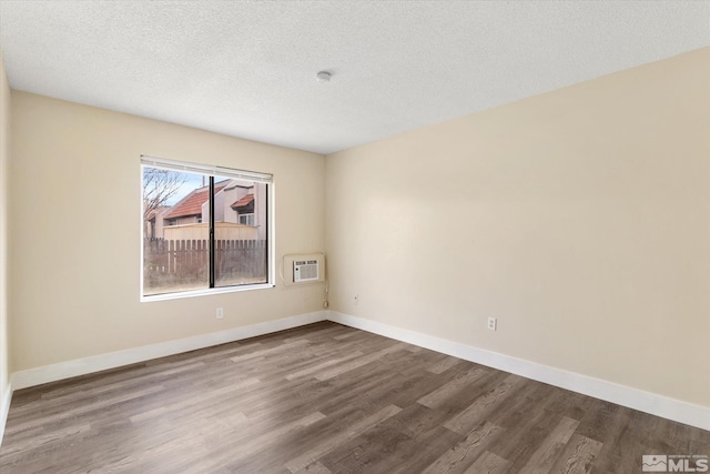 spare room featuring hardwood / wood-style floors, a textured ceiling, and a wall unit AC