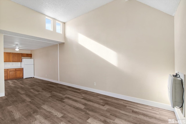 unfurnished living room with ceiling fan, dark hardwood / wood-style flooring, high vaulted ceiling, and a textured ceiling