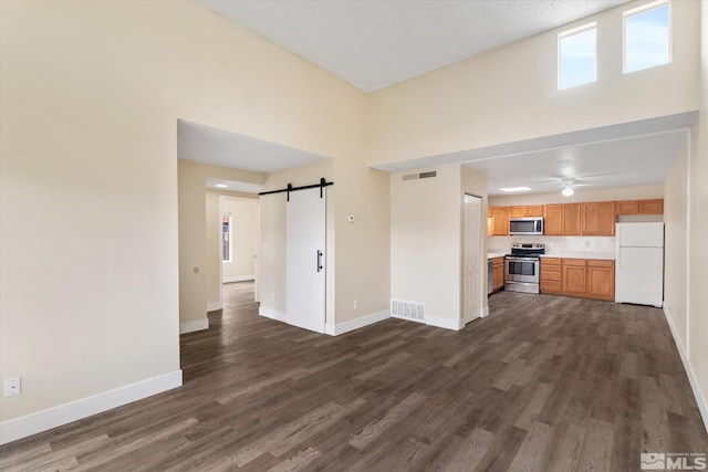 kitchen featuring a barn door, dark wood-type flooring, and stainless steel appliances