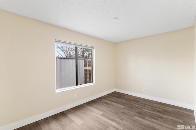 unfurnished room with wood-type flooring and a textured ceiling