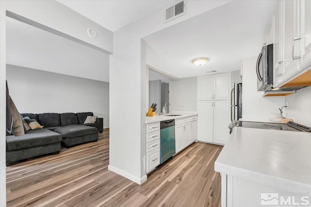 kitchen with stainless steel appliances, white cabinetry, light hardwood / wood-style floors, and sink