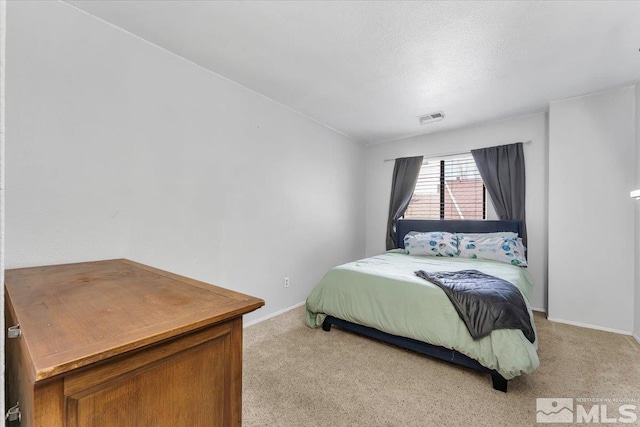 bedroom with light carpet and a textured ceiling