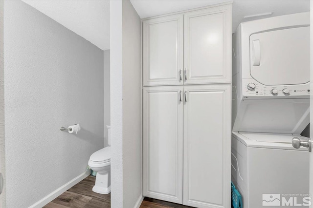 laundry area featuring stacked washer / dryer and dark wood-type flooring