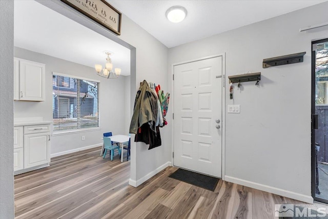 foyer entrance with light hardwood / wood-style flooring and a chandelier