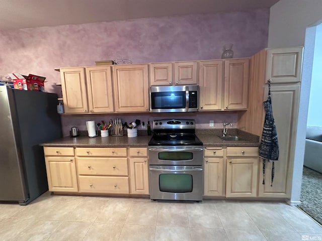 kitchen featuring light brown cabinets, sink, light tile patterned floors, and stainless steel appliances