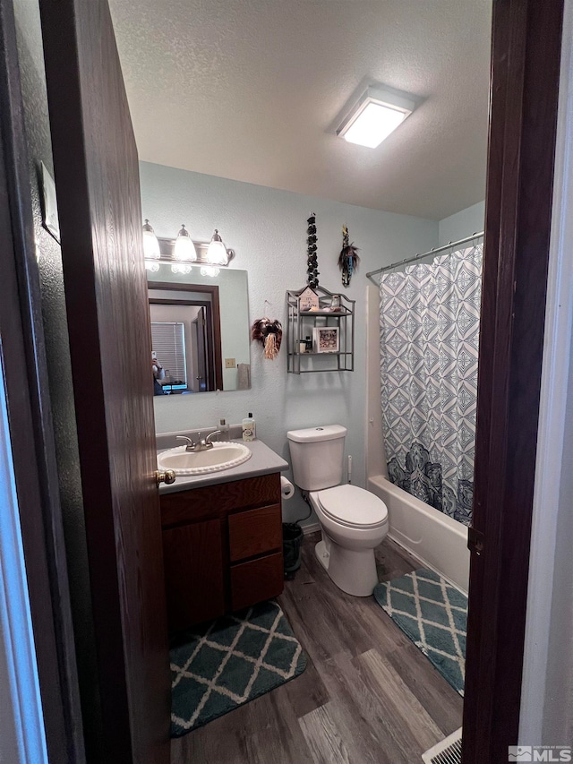 full bathroom featuring vanity, a textured ceiling, shower / bath combo with shower curtain, hardwood / wood-style flooring, and toilet