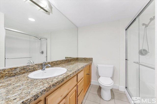 bathroom featuring tile patterned flooring, vanity, a shower with shower door, and toilet