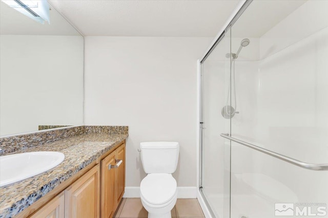 bathroom with tile patterned flooring, vanity, toilet, and a shower with shower door