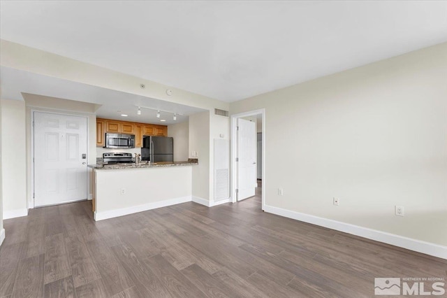 kitchen with light stone counters, dark wood-type flooring, track lighting, and appliances with stainless steel finishes