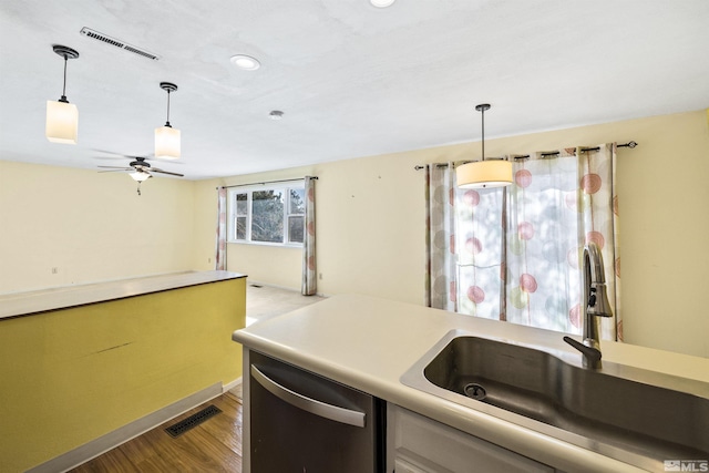 kitchen with sink, dishwasher, decorative light fixtures, and light wood-type flooring