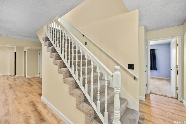 stairway featuring hardwood / wood-style floors and a textured ceiling