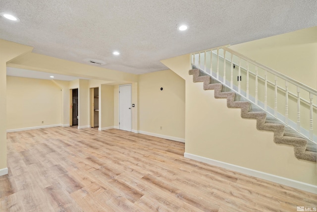 basement featuring light hardwood / wood-style flooring and a textured ceiling