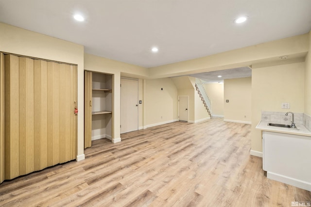 basement with sink and light hardwood / wood-style flooring