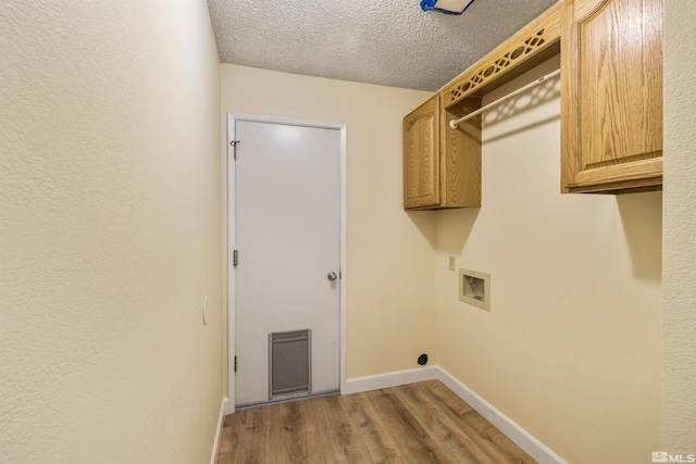 washroom with cabinets, wood-type flooring, a textured ceiling, and washer hookup