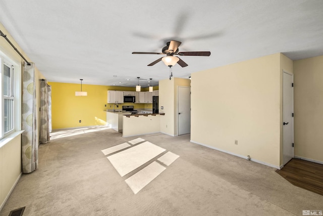 unfurnished living room featuring ceiling fan and light colored carpet