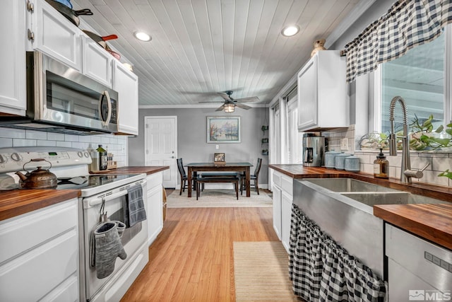 kitchen featuring backsplash, white cabinets, ceiling fan, appliances with stainless steel finishes, and butcher block countertops