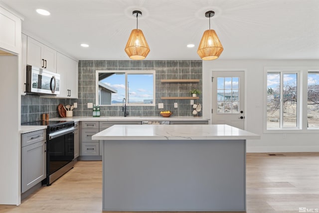 kitchen featuring gray cabinets, hanging light fixtures, a kitchen island, and stainless steel appliances