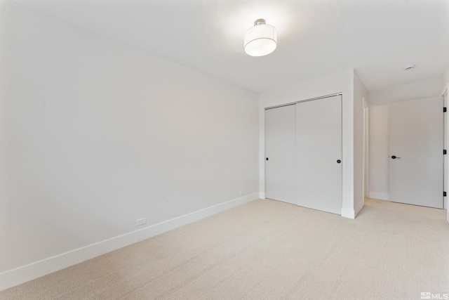 unfurnished bedroom with light colored carpet and a closet