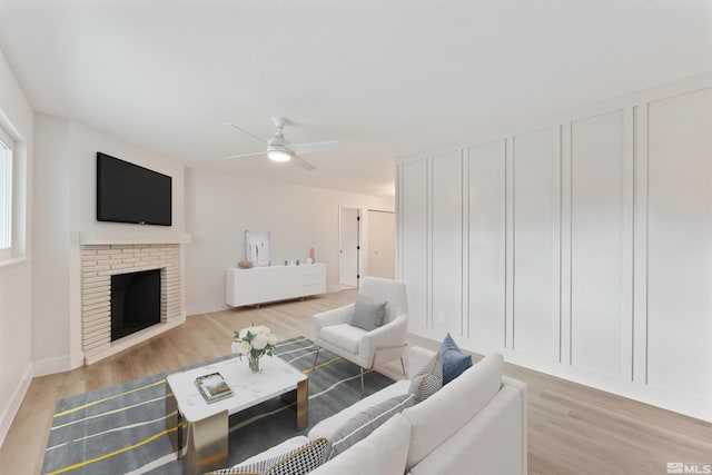 living room with ceiling fan, light wood-type flooring, and a fireplace