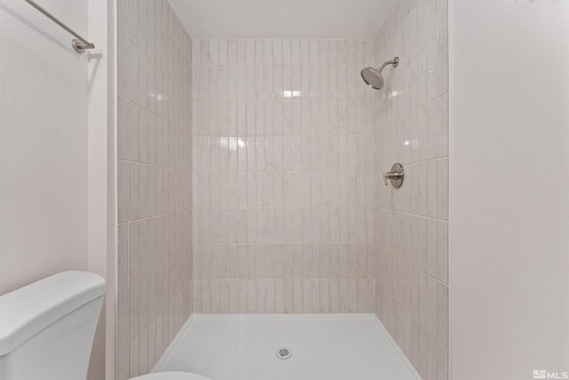 bathroom with a tile shower and toilet