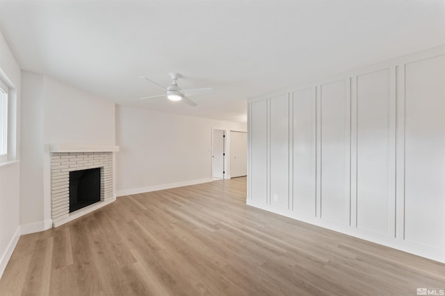 unfurnished living room featuring ceiling fan, light wood-type flooring, and a fireplace