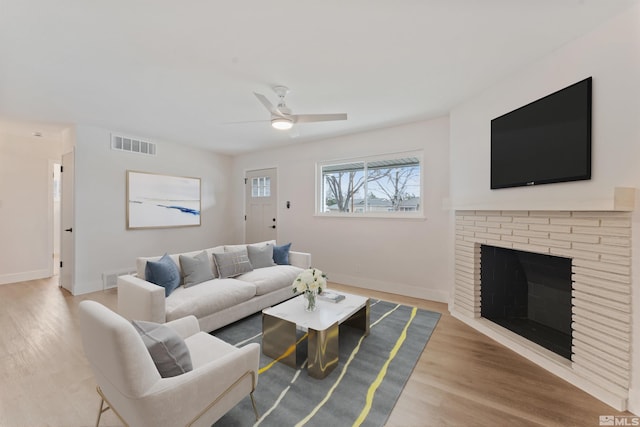 living room with ceiling fan, light wood-type flooring, and a fireplace